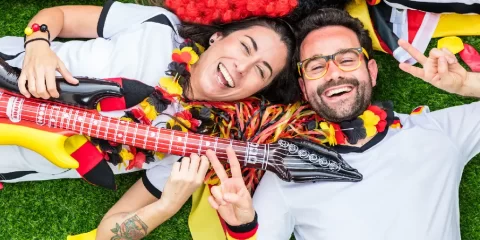 Zwei lachende Fußballfans des deutschen Teams liegen lachend auf einer Wiese